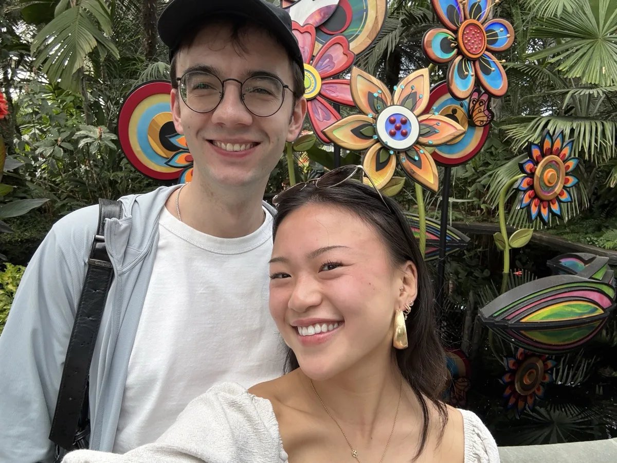 Peter and Lily smiling together in front of colorful flower sculptures